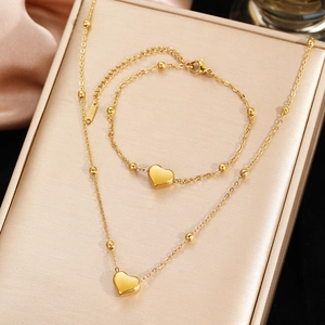 Golden stainless steel heart pendant necklace and bracelet set with beaded chain detail