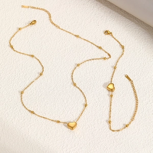Detail of gold beaded necklace and bracelet set with polished heart pendants