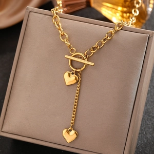 Détail du collier coeur en acier inoxydable doré avec fermoir OT sur une boîte à bijoux