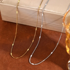 Macro detail of minimalist gold and silver O-chain necklaces with oval metal sequins