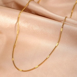 Detail of a gold stainless steel link chain on champagne satin background for women