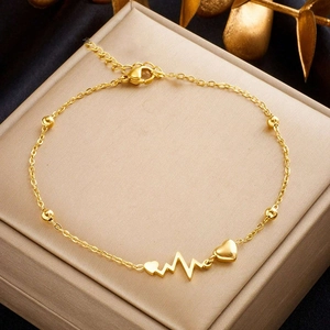 Elegant gold-tone heart and heartbeat pendant anklet with beads on silk background