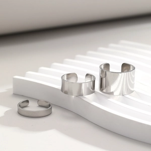 Detailed view of three polished stainless steel open rings in various widths on white steps