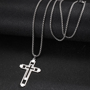 Vue macro d'un pendentif croix creuse argentée avec une chaîne à mailles carrées