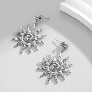 Silver hammered sun spiral earrings on minimalist jewelry display stand