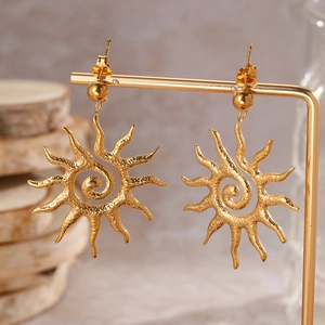 Detailed macro view of gold-toned sunburst drop earrings with hammered spiral texture details