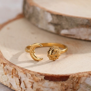 Detail of adjustable golden sun and moon open ring with celestial engraving on wood