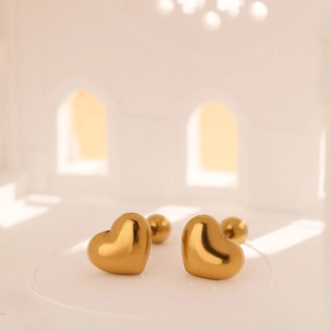 Boucles d'oreilles cœur 3D en or poli avec fermoir à vis sur un piédestal blanc