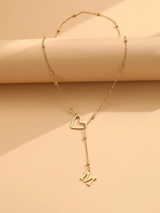Détail macro d'un collier en Y doré avec breloque cœur et pendentif lettre M