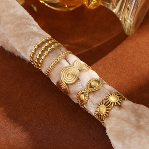 Close-up of five vintage gold-tone stainless steel rings on a beige velvet display stand
