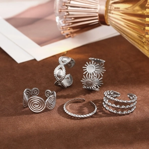 Detail view of five vintage silver-tone bohemian rings with engraved patterns on brown velvet