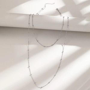 Minimalist silver double layer necklace with small round beads shown in artistic shadow
