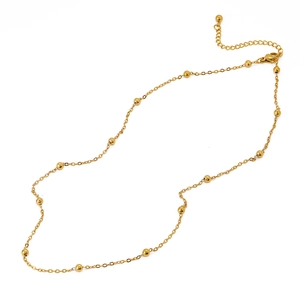 Détail d'un collier chaîne à billes dorées avec fermoir mousqueton et extension réglable