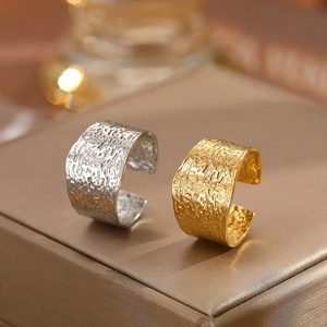 Detail of gold and silver C-shaped wide rings with lava texture on luxury jewelry box