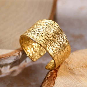 Wide C-shaped gold open ring with lava hammered texture on a rustic wooden stand
