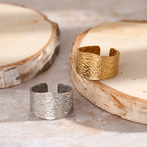 Detailed view of wide C-shape adjustable rings with hammered texture on wood