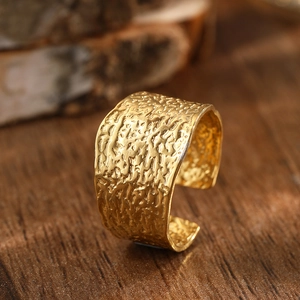 Macro detail of golden wide C-shape ring with irregular hammered lava texture surface