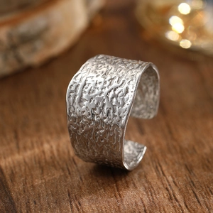 Macro shot of silver-tone wide open ring with hammered texture on wooden surface