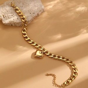 Close-up of golden stainless steel heart anklet with water ripple shadow on stone