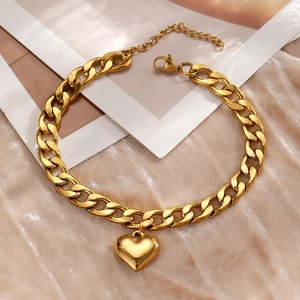 Detailed shot of golden Cuban link anklet with a heart pendant on velvet background