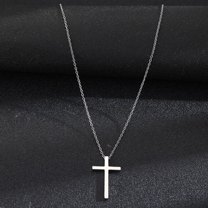 Polished stainless steel cross pendant on fine chain over black matte background