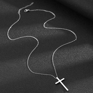 Polished stainless steel cross pendant necklace with a fine chain on black fabric