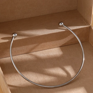 Detailed view of minimalist stainless steel open torque necklace with polished silver beads