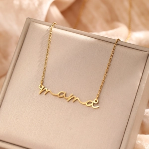 Close-up of a gold-plated mama letter pendant on a fine chain over silk fabric