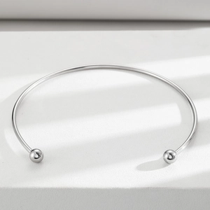 Minimalist silver stainless steel collar necklace with polished beads on marble surface