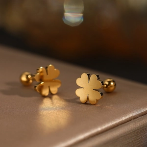 Macro view of gold stainless steel four-leaf clover stud earrings with screw ball backs