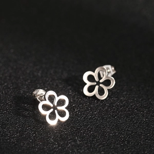 Macro shot of silver hollow five-petal flower earrings with metallic finish