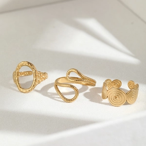 Close-up of three gold adjustable rings featuring hammered texture and cross design