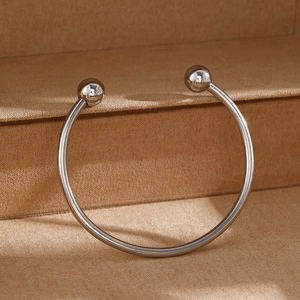 Minimalist stainless steel open bangle with polished beads on a display stand
