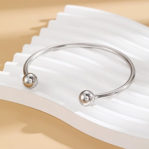 Detail showing polished silver steel bangle with metal balls on white wavy stone