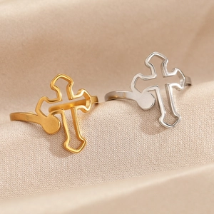 Macro detail of gold and silver cutout cross open rings on premium satin fabric texture