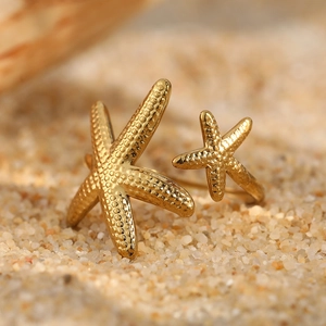Gold starfish toe ring in stainless steel with textured sea design on beach sand