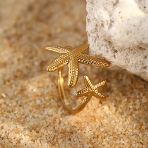 Detailed macro view of gold starfish open rings on sand with realistic sea textures