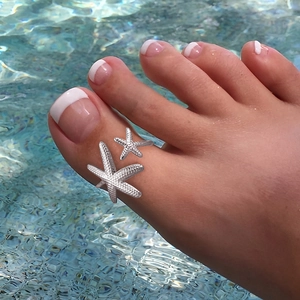 Adjustable stainless steel starfish toe ring with textured finish on a summer beach background