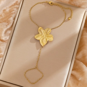 Detail of 18K gold-plated stainless steel hand chain with a sun flower charm on velvet