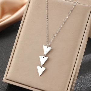 Polished silver triple triangle drop necklace on a beige leather display stand
