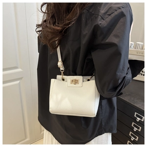 Détail d'un sac bandoulière en cuir grainé blanc crème avec fermoir doré tournant