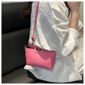 Détail du sac bandoulière en cuir rose avec fermoir rotatif en métal doré