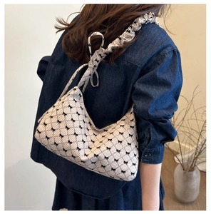 Detail of checkered bow print shoulder bag with ruffled strap on a crescent crescent base