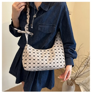 Detail of beige plaid hobo bag with black bows worn with a navy denim dress