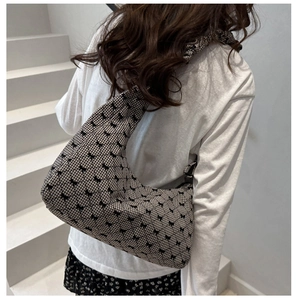 Detail of gingham shoulder bag with black bow embroidery and ruched strap on a model