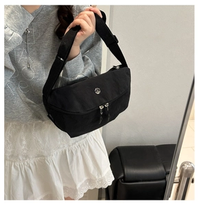 Détail du sac croissant en nylon noir avec logo argenté et double fermeture éclair