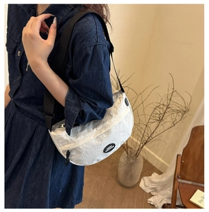 Close-up of white crescent crossbody bag with black strap and Lucky Fashion logo label