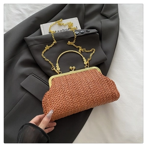 Détail d'un sac de soirée tressé en paille avec poignée en métal doré et chaîne