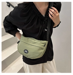Detail of green nylon crescent bag with Lucky Fashion patch and black adjustable strap