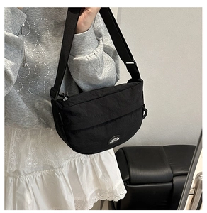 Mirror selfie showing the black half-moon nylon crossbody bag with adjustable wide strap